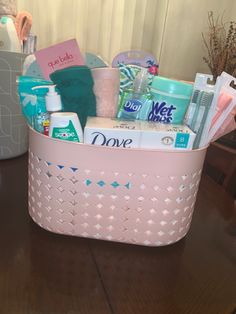 a pink basket filled with personal care items on top of a wooden table in front of a window