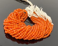 an orange and white beaded necklace on a black surface