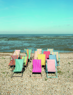 colorful lawn chairs are lined up on the beach