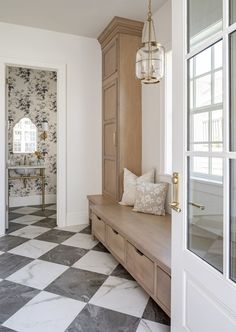 a hallway with a checkered floor and wooden bench next to a mirror on the wall