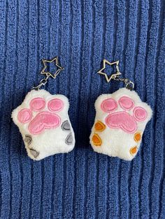 two small stuffed animal keychains with pink and orange paw prints on them sitting on a blue towel