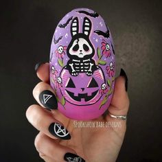 someone is holding an easter egg decorated with skulls and flowers