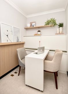 a white desk with a laptop on top of it next to two chairs and a plant