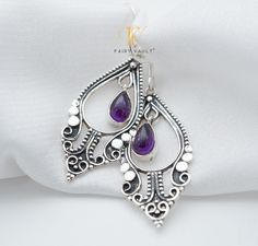 Elevate your style with these exquisite handcrafted drop earrings, featuring lustrous violet amethyst cabochons set in sterling silver. Our talented artisans have meticulously crafted each piece to perfection, adding intricate fine detailing that sets them apart. Benefits: Natural Beauty: Our amethyst cabochons showcase the natural beauty and unique color variations of genuine amethyst, making each earring one of a kind. Elegance and Versatility: These earrings effortlessly transition from casua Elegant Purple Cabochon Earrings, Purple Teardrop Bohemian Earrings, Teardrop Cabochon Earrings For Anniversary, Purple Sterling Silver Teardrop Earrings For Gift, Purple Gemstone Teardrop Earrings, Traditional Purple Drop Earrings, Handmade Amethyst Teardrop Earrings, Purple Amethyst Teardrop Earrings For Pierced Ears, Teardrop Amethyst Earrings For Gift