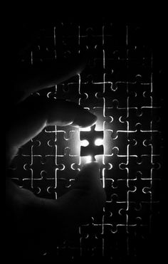 a person holding a piece of a puzzle in their hand with the light shining through it