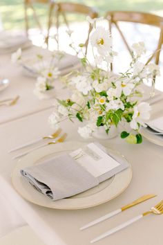 the table is set with white flowers and silverware