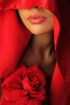 a woman with a red rose in her lapel and hood over her head is looking at the camera