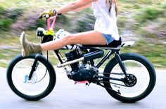 a woman riding on the back of a black and white bike with her legs spread out