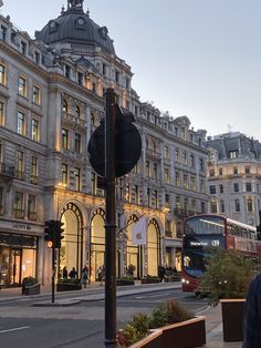 a double decker bus is driving down the street in front of a building at dusk