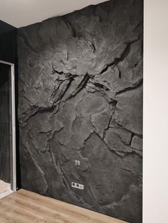 a black and white wall in a room with wood flooring next to a glass door