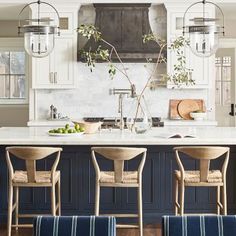 a kitchen with blue cabinets and white countertops is pictured in this image, there are four chairs at the center of the island