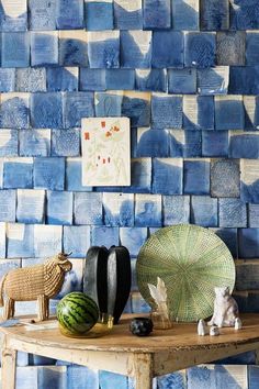 a table topped with lots of blue tiles next to a wall covered in sheep figurines