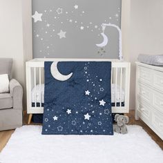 Shooting Stars 4 Piece Crib Bedding Set by Sammy & Lou® in stylized room. The wall is accented with cream pillars and a gray accent wall with scattered stars. The floor is made of a natural wooden flooring and a white rug. The nursery quilt, crib sheet and skirt, and coordinating celestial mobile (sold separtely) sit on a modern white crib with natural wooden feet. The elephant plush toy sits in front of the crib. A white dresser and gray rocking chair accents the sides of the nursery. Celestial Nursery Theme, Galaxy Nursery, Babies Rooms, Gray Palette, Nursery Idea, Perfect Nursery, Baby Crib Bedding Sets, Blue Bedding Sets, Clouds Nursery