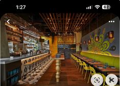 an image of a restaurant with yellow chairs and wooden tables in front of the bar