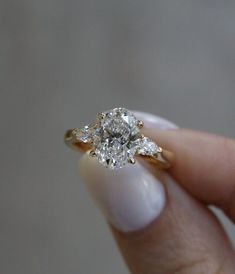 a woman's hand holding a diamond ring with three stones on the top and bottom