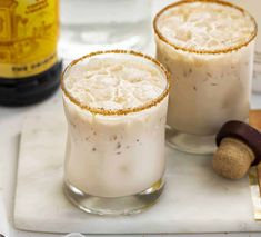 two glasses filled with white liquid sitting on top of a counter