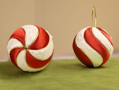 two red and white ornaments sitting on top of a green tablecloth covered floor next to each other