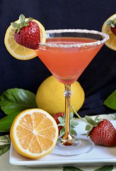 a strawberry margarita sitting on top of a white plate next to lemons and strawberries