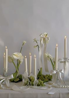 a table topped with lots of white flowers next to candles and pearls on top of it