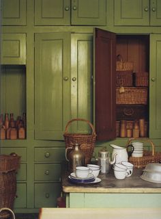 a kitchen with green cabinets and white dishes