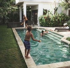 a young boy playing with a frisbee in a pool next to a house