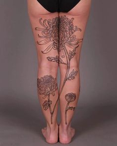 a woman's legs with tattoos on them and flowers in the bottom right leg