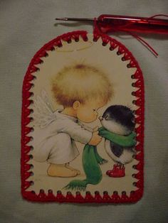 a little angel hugging a penguin with a green scarf around it's neck on a white sheet