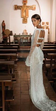 a woman in a white dress is standing in front of pews at a church