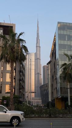 a white truck driving down a street next to tall buildings with palm trees in the foreground