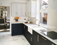 a kitchen with marble counter tops and black cabinets, gold pulls on the faucets