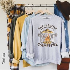 Our Life is better by the campfire pullover is the perfect addition to any wardrobe! We create custom sweatshirts with great designs for everyone's liking. If you don't find the size or colour you would like, please message us and we will be happy to accommodate! PRODUCT We use the finest premium Gildan 18000 crewneck sweatshirts for you, they are feather soft and very breathable with a good stretch. These sweatshirts are known for their great quality and much loved by our consumers. SIZING This Long Sleeve T-shirt With Letter Print For Camping, Winter Outdoor T-shirt With Relaxed Fit, Winter Camping Graphic Print Tops, Relaxed Fit Graphic Sweatshirt For Camping, Crew Top For Fall Outdoor Activities, Graphic Print T-shirt For Fall Camping, Fall Crew Neck Tops For Outdoor Activities, Crew-neck Tops For Outdoor Activities In Fall, Crew Neck Cotton Sweatshirt For Camping