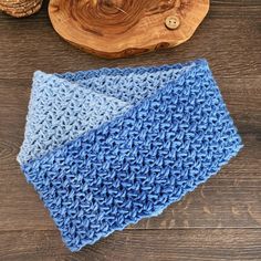 a blue crocheted dishcloth next to a wooden bowl