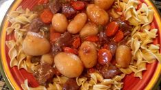 a red plate topped with pasta and meat covered in sauce