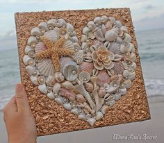 a hand holding up a heart made out of seashells