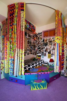 a bedroom with colorful bedding and curtains on the walls, in front of a purple carpeted floor