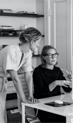 two women at a desk looking at a computer screen