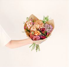 a person holding a bouquet of flowers in their hand