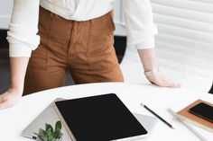 a person standing at a table with a tablet and pen in front of them on it