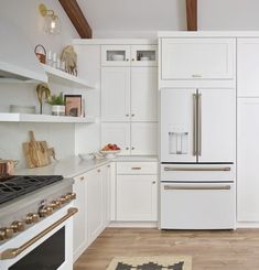 a kitchen with white cabinets and an oven in the center is seen from across the room