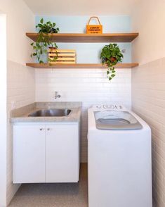 a washer and dryer in a small room with plants on the shelves above