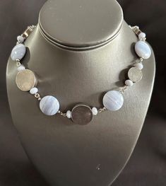 This piece features stunning flat round blue lace agate beads paired with intricate Thai silver flat round beads, creating a unique and eye-catching design. The necklace is adjustable, measuring between 22 to 27 inches in length for a perfect fit. Adjustable Silver Beaded Necklace With Large Beads, Elegant Adjustable Beaded Necklaces With Round Pendant, Elegant Beaded Necklace With Adjustable Round Pendant, Elegant Beaded Necklaces With Adjustable Round Pendant, Adjustable Silver Beads Necklace With Round Pendant, Adjustable Silver Beaded Necklace With Round Pendant, Elegant Adjustable Beaded Necklace With Round Pendant, Adjustable Round Necklace With Silver Beads, Silver Beaded Necklace With Gemstone Beads