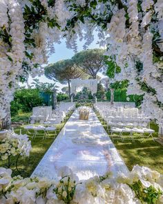 an outdoor ceremony setup with white flowers and greenery on the grass, surrounded by trees