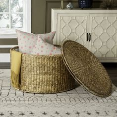 a wicker basket sitting on top of a rug next to a white cabinet and window