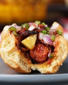 a sausage sandwich with pineapple and onions on a plate