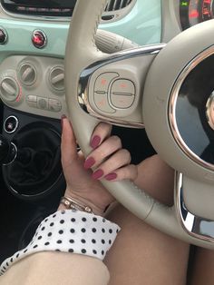 a woman sitting in the drivers seat of a car with her hands on the steering wheel