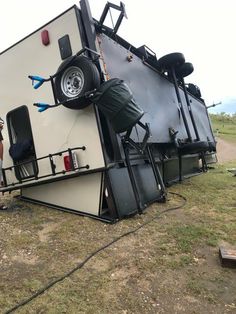 a man standing next to a trailer that has been flipped over