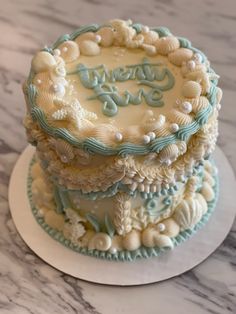 there is a three layer cake on top of the table, decorated with seashells