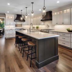 a large kitchen with an island in the middle and four stools at the end