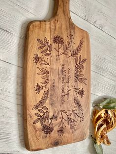 an engraved wooden cutting board with leaves and flowers on it next to a piece of bread