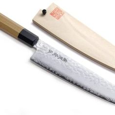 two knives are sitting next to each other on a white surface with a wooden handle